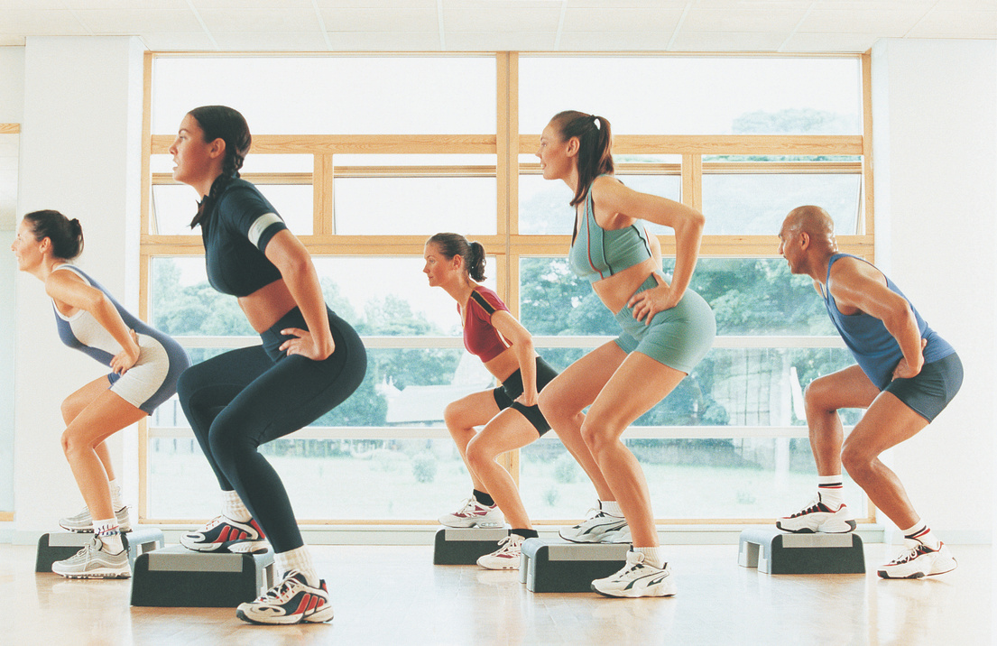 Three women in step workout class doing lateral lunges